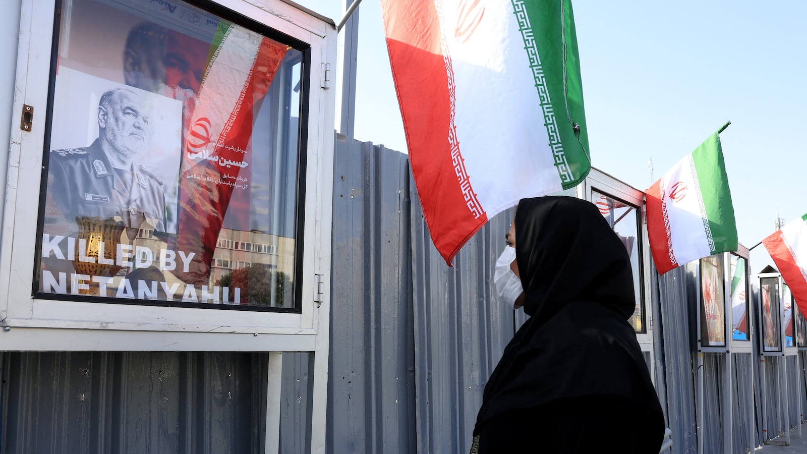 An Iranian woman looks at an image of slain Iranian Islamic Revolutionary Guard Corps (IRGC) commander Hossein Salami, killed following Israeli strikes on targets in Iran