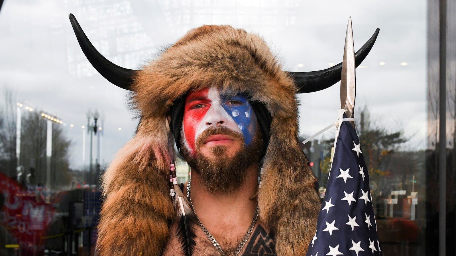Jacob Chansley, also known as Jake Angeli, with his face painted in the colors of the U.S. flag, poses for a picture as supporters of U.S. President Donald Trump gather.