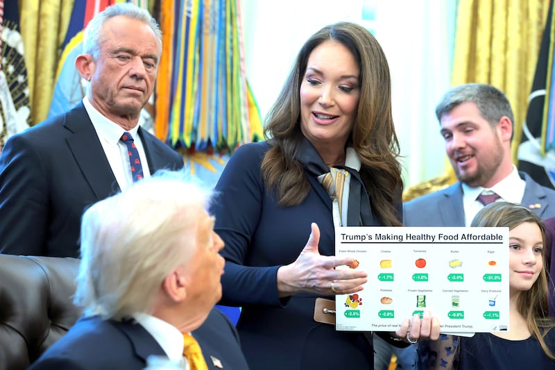 Secretary of Agriculture Brooke Rollins (C) speaks as U.S. Secretary of Health and Human Services Robert F. Kennedy Jr. (L) and U.S. President Donald Trump look on