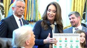 Secretary of Agriculture Brooke Rollins (C) speaks as U.S. Secretary of Health and Human Services Robert F. Kennedy Jr. (L) and U.S. President Donald Trump look on