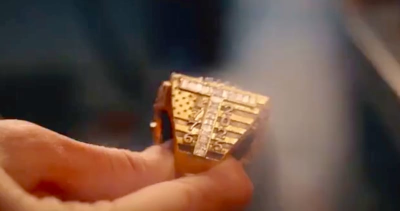 Gold ring with jeweled ‘T’.