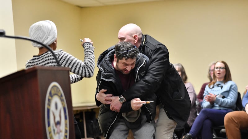 A man is tackled after spraying an unknown substance at US Representative Ilhan Omar (D-MN) (L) during a town hall she was hosting in Minneapolis, Minnesota, on January 27, 2026. (Photo by Octavio JONES / AFP via Getty Images)