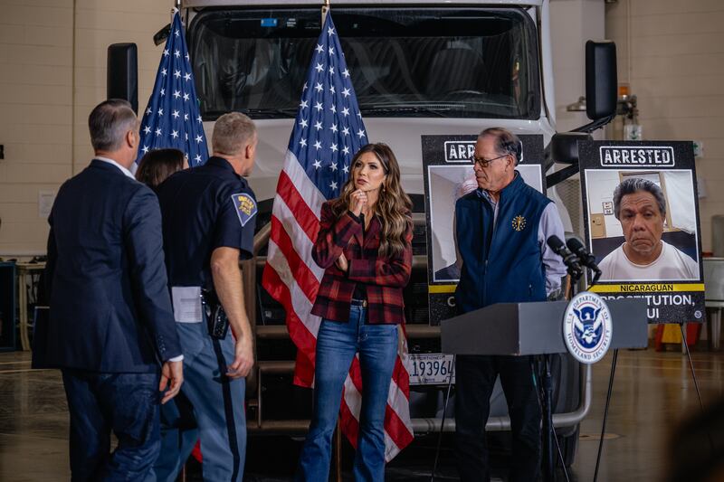 U.S. Secretary of Homeland Security Kristi Noem (C) speaks with officials following a press conference