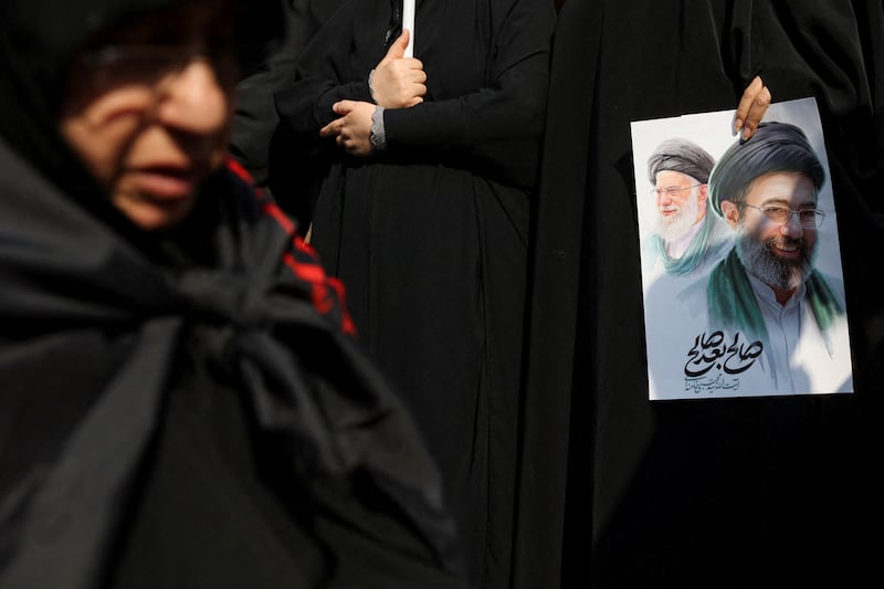 A woman holds an image of Iran's new supreme leader, Mojtaba Khamenei, alongside late Iranian Supreme Leader Ayatollah Ali Khamenei. Majid Asgaripour/WANA (West Asia News Agency) VIA REUTERS