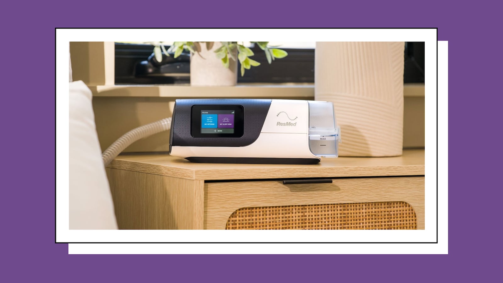 The ResMed AirSense 11 CPAP Machine on a nightstand in a lit bedroom.