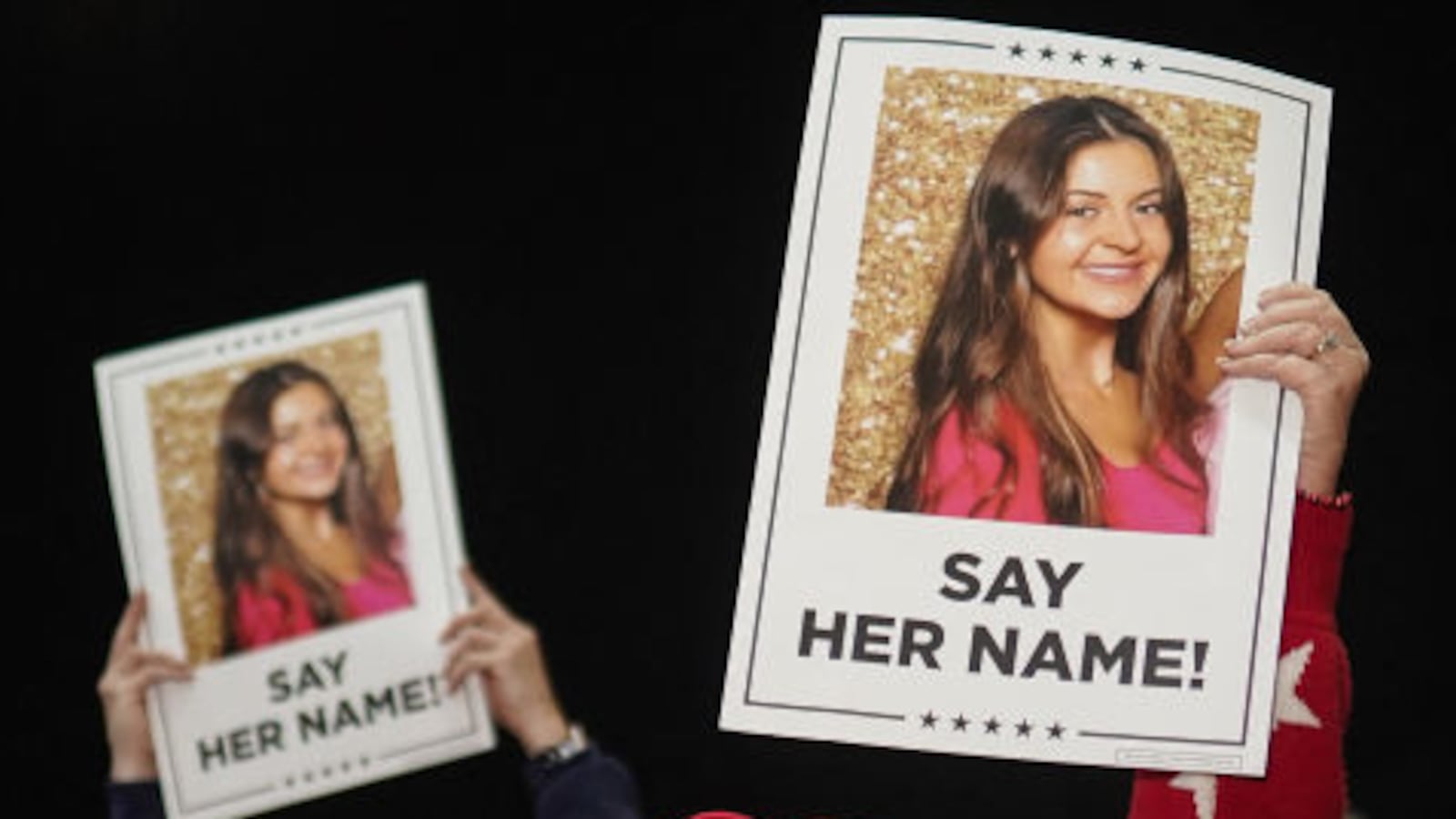 Supporters of Donald Trump hold up photos of Laken Riley and posters that say, “SAY HER NAME.”