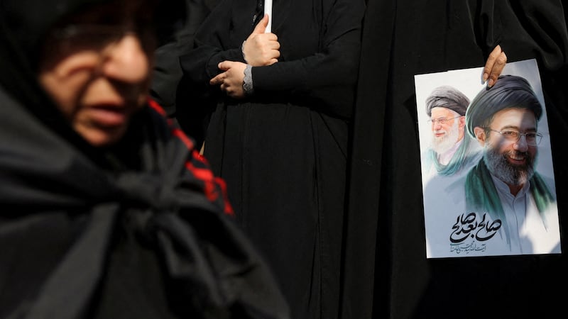 A woman holds an image of Iran's new supreme leader, Mojtaba Khamenei, alongside late Iranian Supreme Leader Ayatollah Ali Khamenei. Majid Asgaripour/WANA (West Asia News Agency) VIA REUTERS