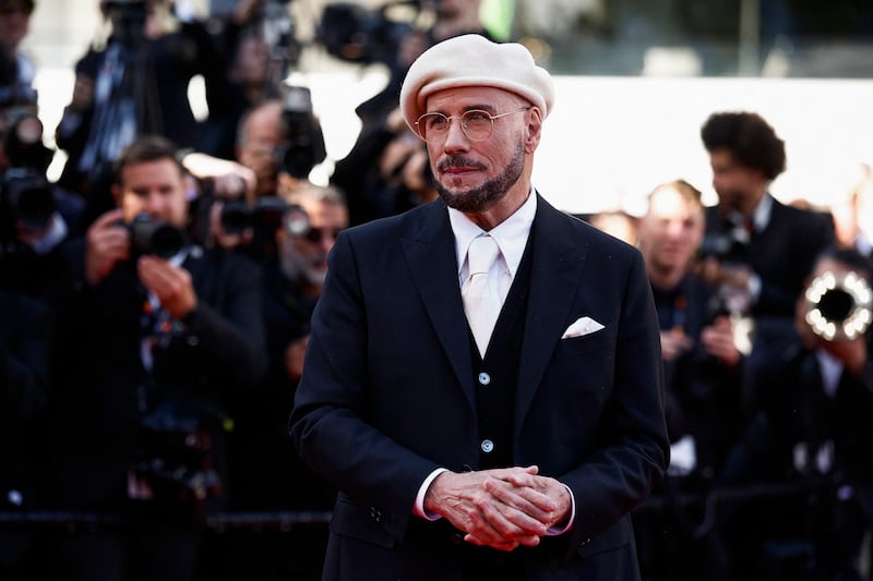 Director John Travolta poses in a white beret on the red carpet during guest arrivals before the screening of his film "Propeller One-Way Night Coach" in 2025.
