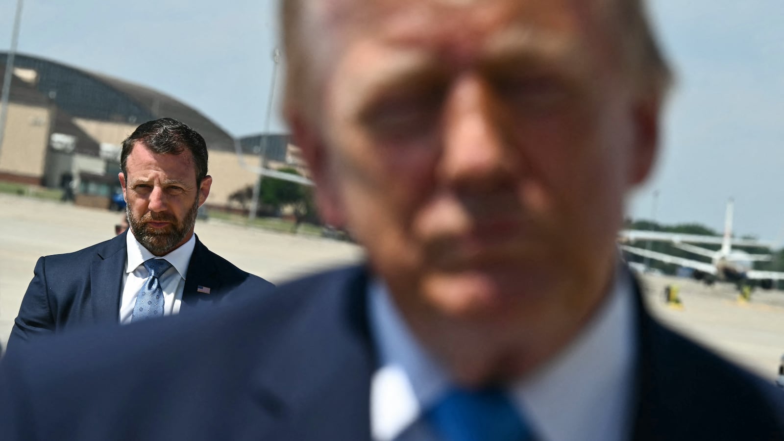 US Secretary of Homeland Security Markwayne Mullin looks on as President Donald Trump speaks to reporters after stepping off Air Force One.