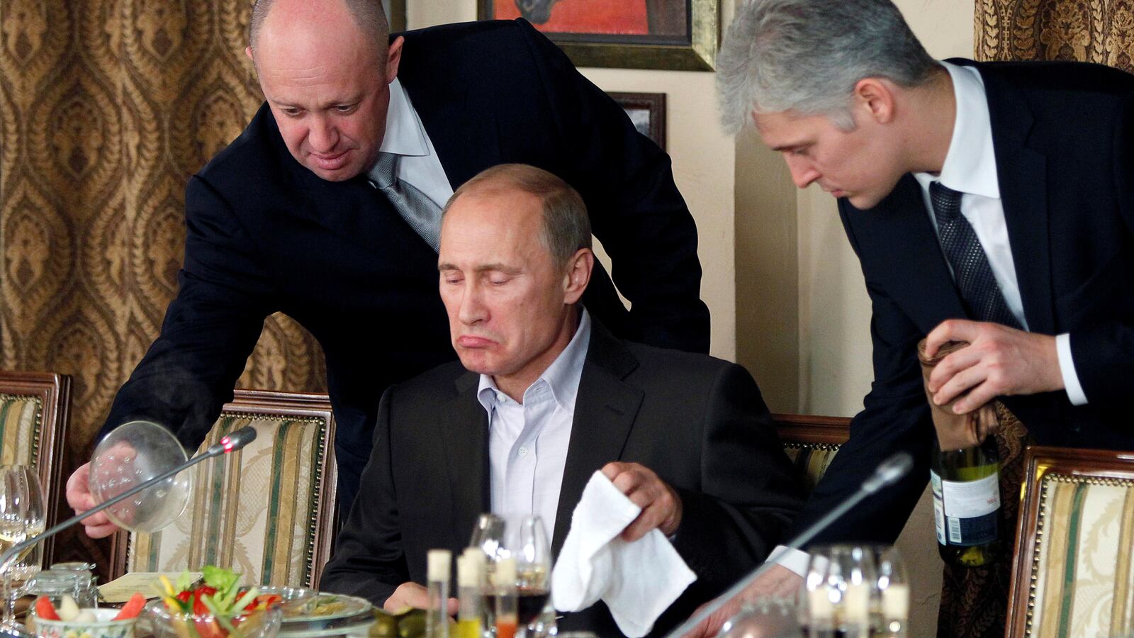 Yevgeny Prigozhin (L) assists Vladimir Putin during a dinner at the restaurant Cheval Blanc outside Moscow, Russia, Nov. 11, 2011.