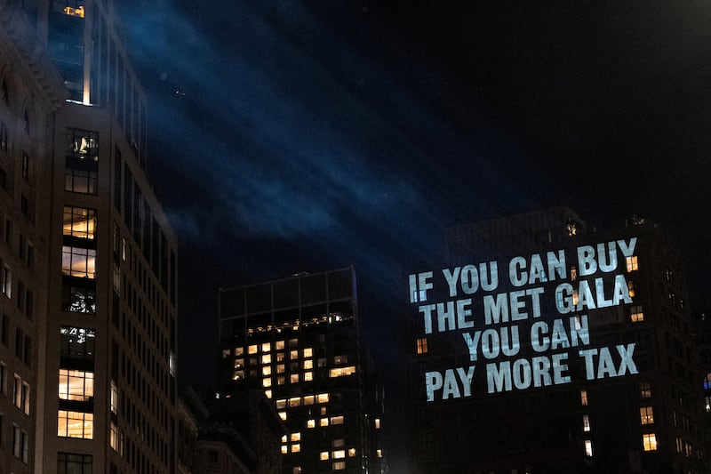 Activists project protest messages, highlighting issues of wealth inequality, climate accountability, and labor rights, onto the facade of a building which can be seen from Jeff Bezos' penthouse, on the eve of the Met Gala, the star-studded fundraiser known for its extravagant fashion and high-profile guests, in New York City, U.S., May 3, 2026.
