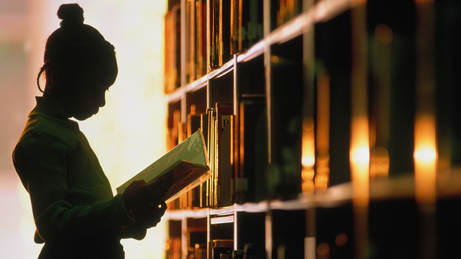 A girl reading a book in a library.