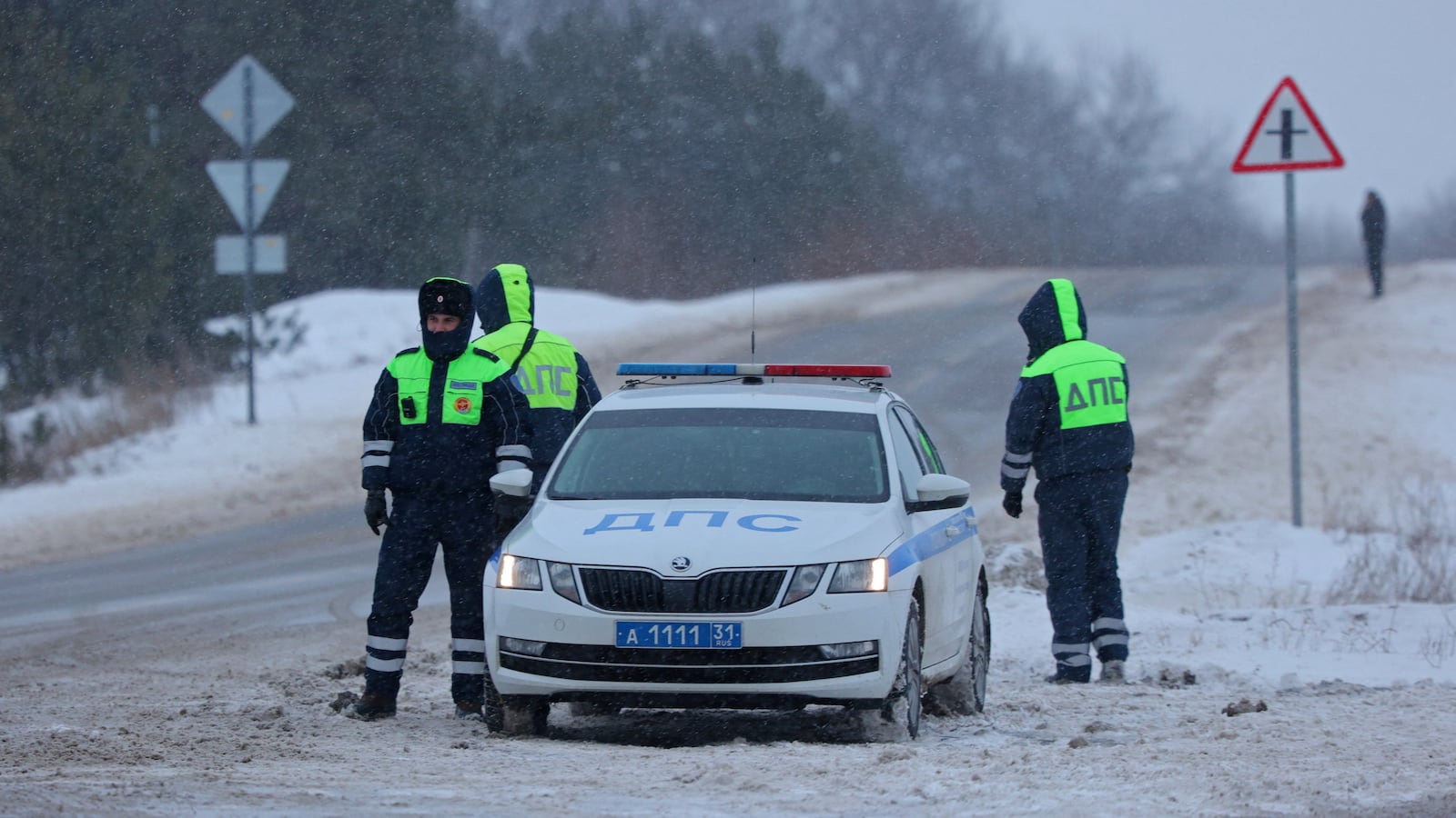 Traffic police officers stand guard on a road near the crash site of the Russian Ilyushin Il-76 military transport plane outside the village of Yablonovo in the Belgorod Region.