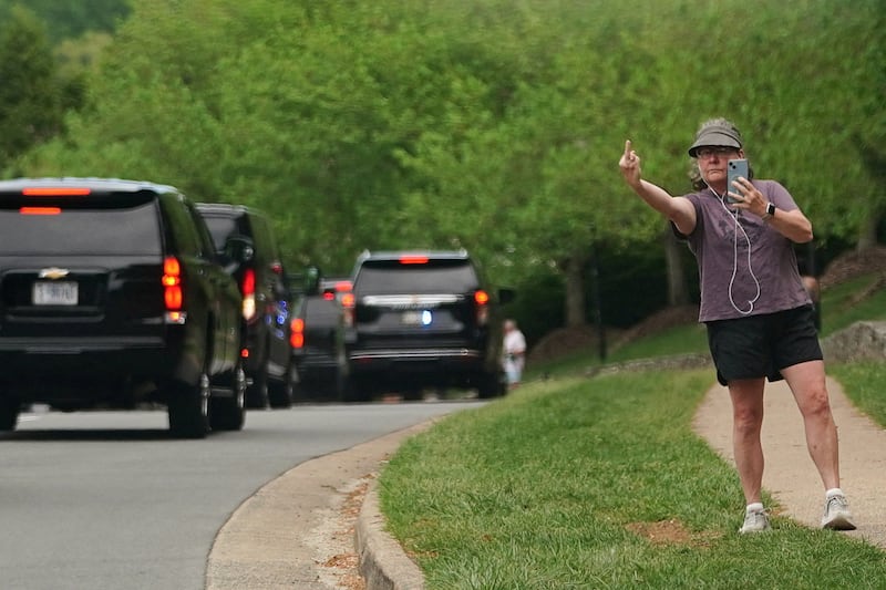 A pedestrian gestures toward the motorcade of U.S. President Donald Trump, as the president travels to Trump National Golf Club, in Sterling, Virginia.