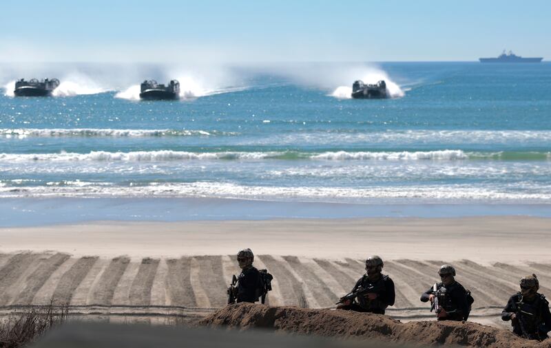 OCEANSIDE, CALIFORNIA - OCTOBER 18: A team of U.S. Navy SEALS take a position on the beach as a group of Landing Craft Air Cushion's (LCAC) approach the beach behind them during the America's Marines 250 event at Camp Pendleton's Red Beach on October 18, 2025 in Oceanside, California. The U.S. Marines are marking their 250th anniversary with a live amphibious assault demonstration entitled "Sea To Shore--A Review of Amphibious Strength" and visits from Vice President JD Vance and War Secretary Pete Hegseth.  (Photo by Mario Tama/Getty Images)