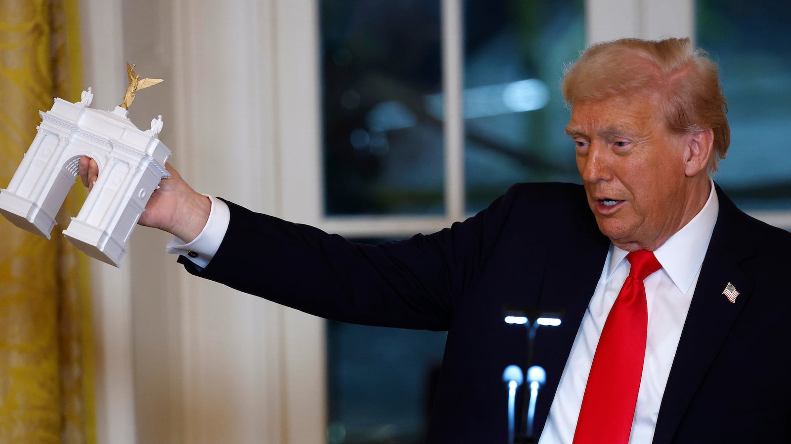 Trump holds a model of an arch
