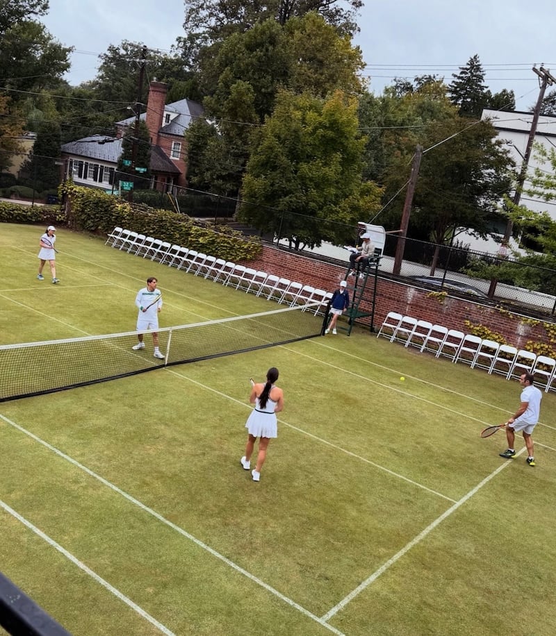 People playing doubles tennis on grass