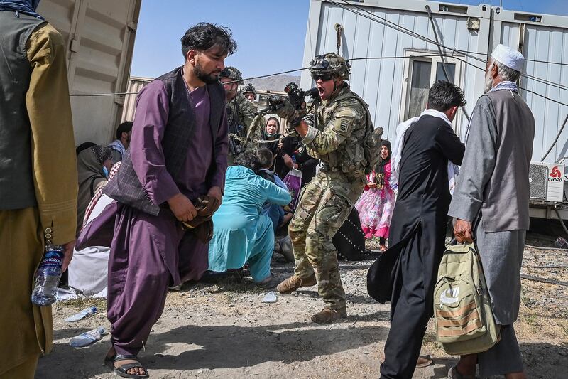 An American soldier point his rifle towards an Afghan passenger at the Kabul airport in Kabul on Aug. 16, 2021, during America's withdrawal from Afghanistan.