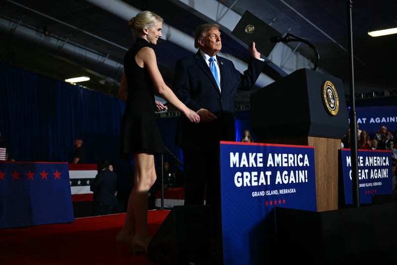 Executive assistant to President Donald Trump, Natalie Harp, stands next to President Donald Trump as he holds up an executive order during a campaign rally at Pinnacle Bank Expo Center in Grand Island, Nebraska, on October 5, 2026.