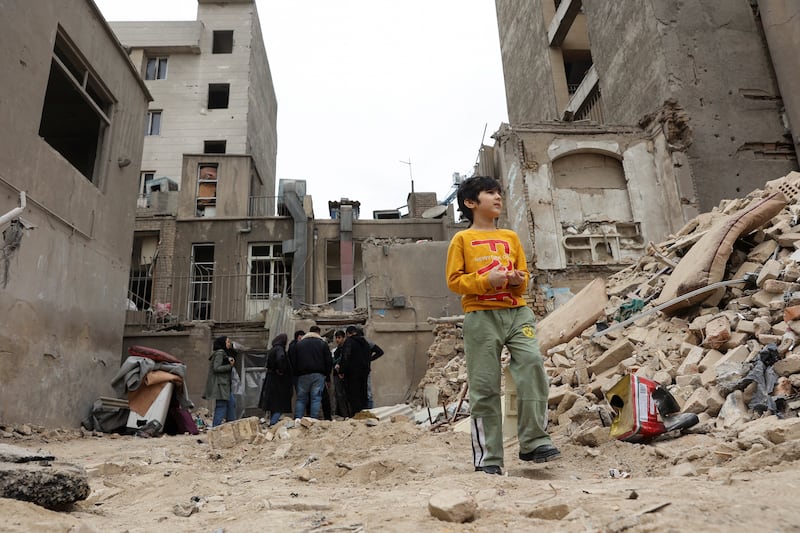 A boy stands near a house that was damaged by a strike, amid the U.S.-Israeli conflict with Iran, in Tehran, Iran, March 15, 2026.