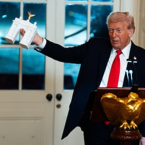 President Donald Trump holds up a model of an arch while delivering remarks during a ballroom fundraising dinner in the East Room of the White House on Wednesday October 15, 2025.