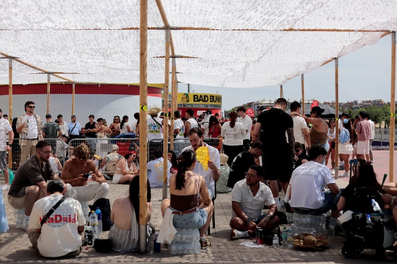 People take shelter from the heat outside the venue for Puerto Rican singer Bad Bunny's "DeBI TiRAR MaS FOToS World Tour" concert in Madrid, Spain, June 6, 2026. REUTERS/Marta Montana Gomez