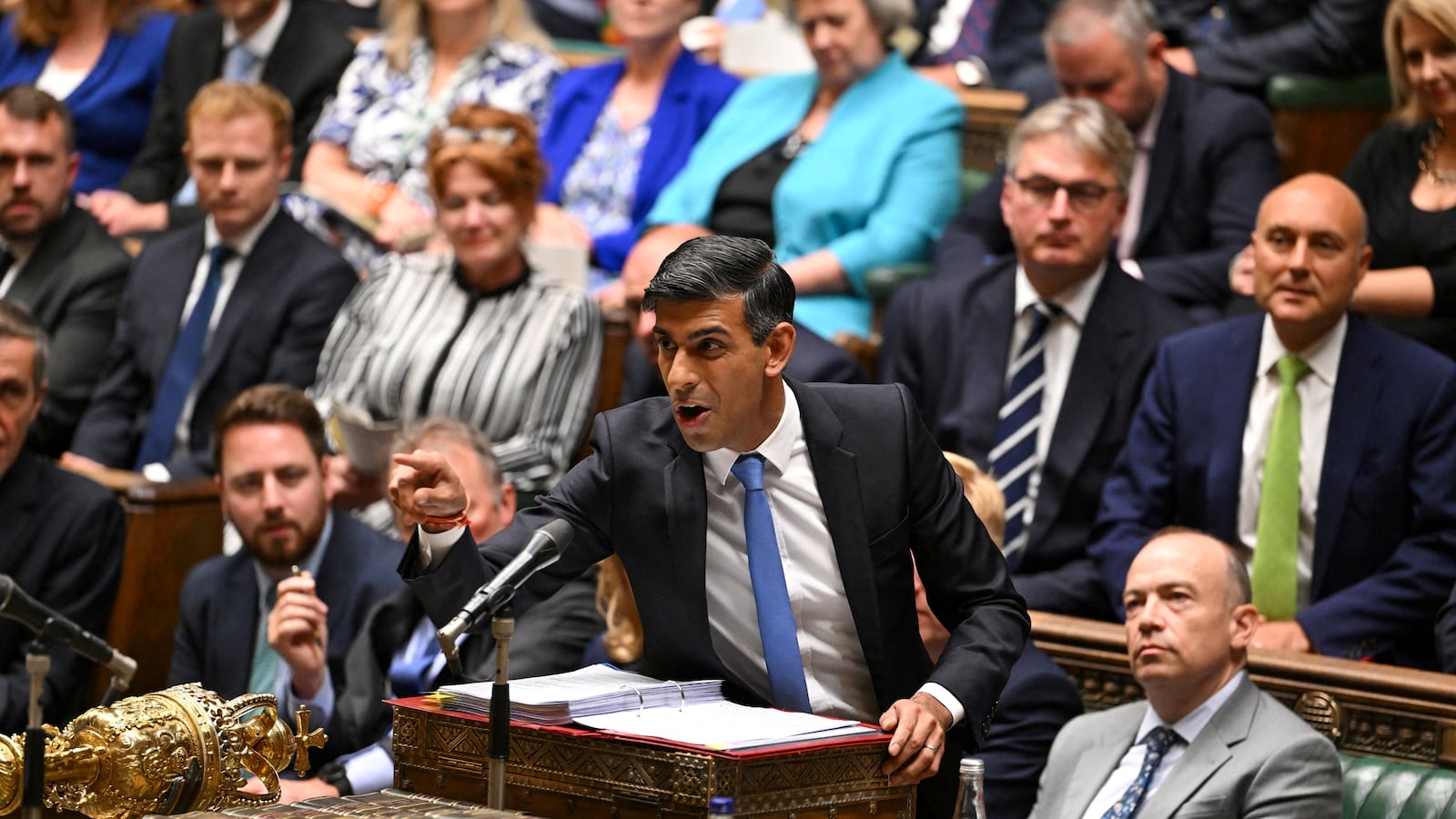 Rishi Sunak speaking at a podium with people seated behind him.