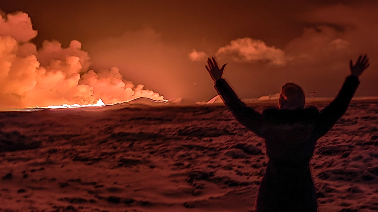 A local resident watch smoke billow as the lava colour the night sky orange from an volcanic eruption on the Reykjanes peninsula 3 km north of Grindavik, western Iceland on December 18, 2023.