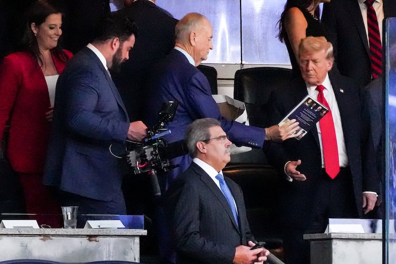 Bill O'Reilly hands U.S. President Donald Trump a book as he attends the Yankees Baseball Game at Yankee Stadium in New York City, U.S., September 11, 2025. REUTERS/Ken Cedeno
