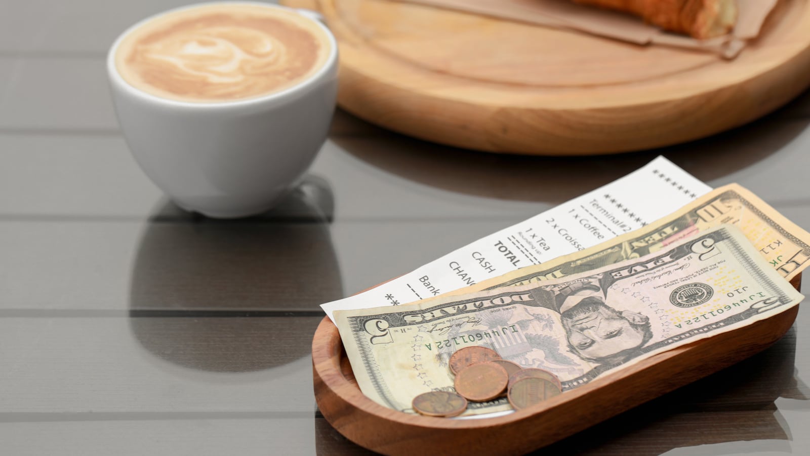 Tips, receipt and cup with coffee on wooden table