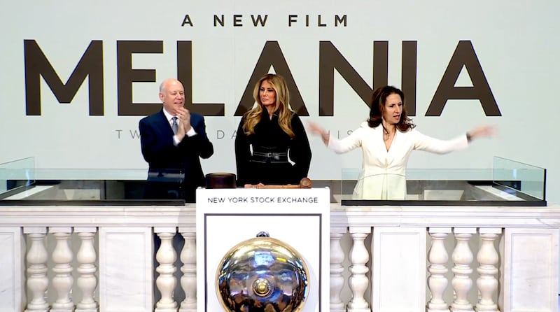 A woman gestures to the right of Melania Trump