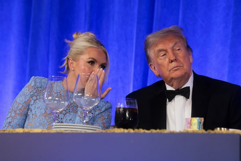 White House Press Secretary Karoline Leavitt speaks to U.S. President Donald Trump at the White House Correspondents' Association (WHCA) Dinner, which was rescheduled from April after it was interrupted when a man tried to force his way through security and fired a shotgun, at the Waldorf Astoria hotel in Washington, D.C.
