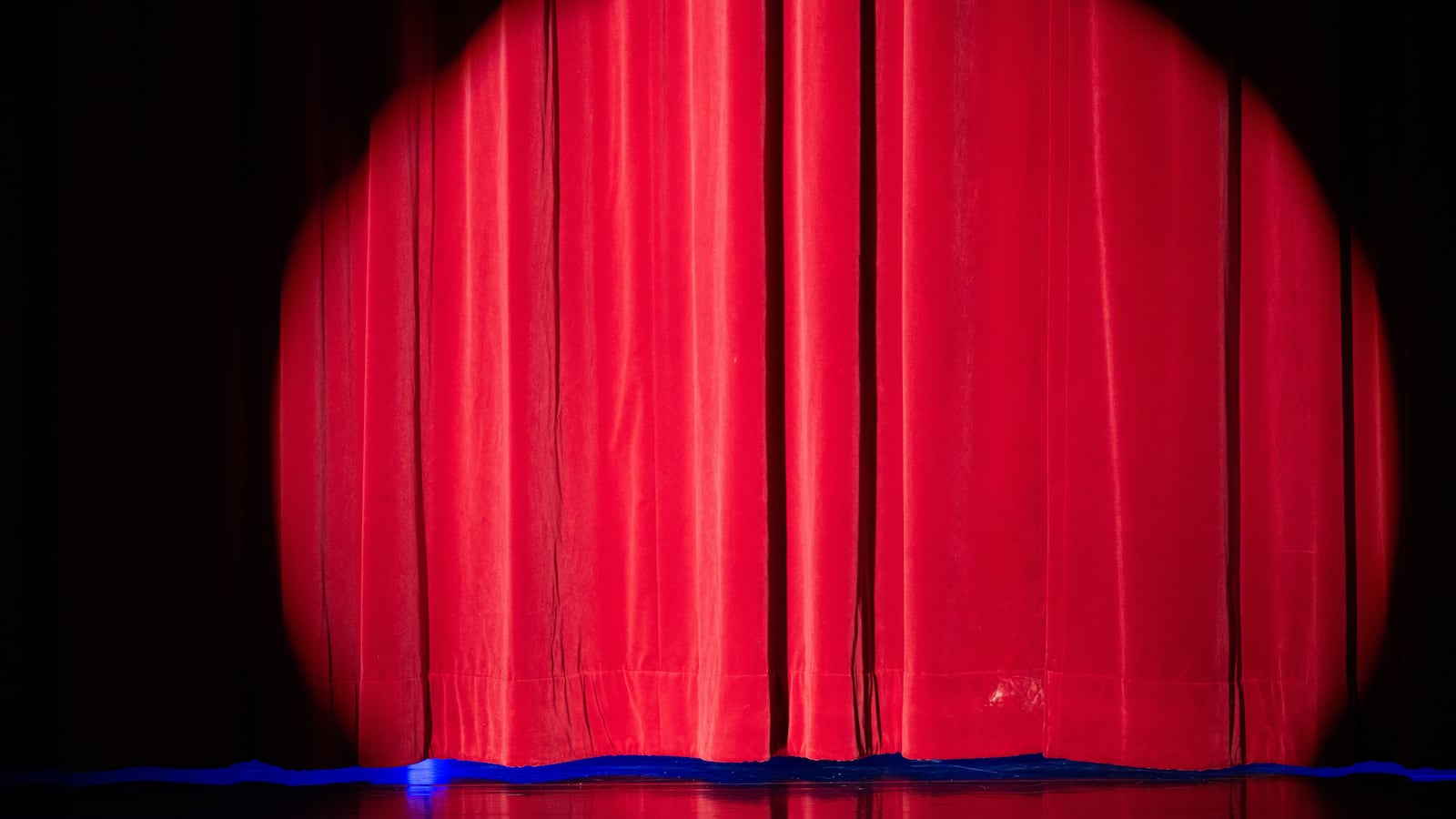 A spotlight illuminates the curtain on stage.