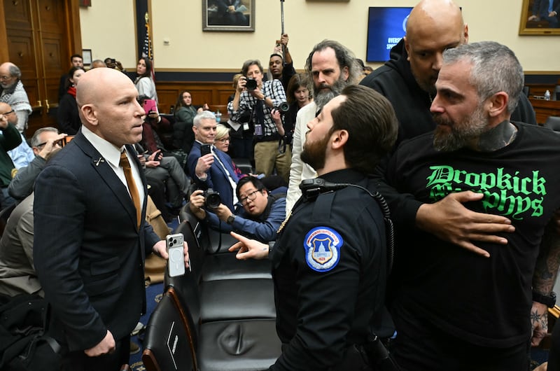 A U.S. Capitol Police officer intervenes as far-right political operative Ivan Raiklin (left) confronted former Metropolitan Police Department officer Michael Fanone (right) as he's held back by former U.S. Capitol Police Officer Harry Dunn during a break in testimony by former Special Counsel Jack Smith before the House Judiciary Committee on January 22, 2026.