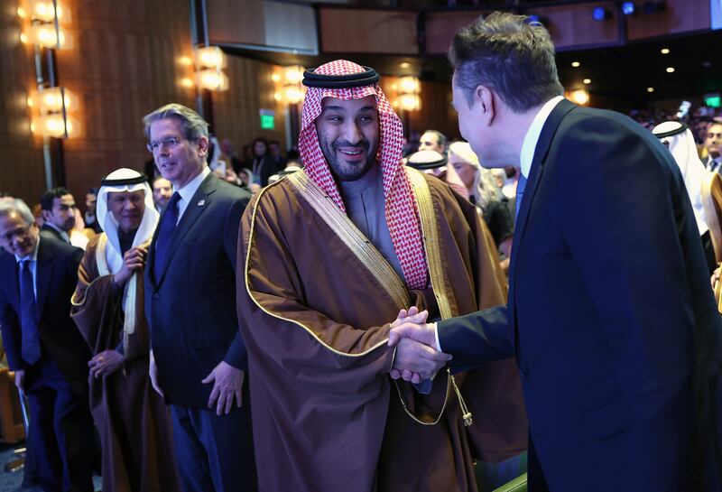 WASHINGTON, DC - NOVEMBER 19: Crown Prince and Prime Minister Mohammed bin Salman of Saudi Arabia greets Tesla CEO Elon Musk as they take their seats to listen to U.S. President Donald Trump deliver remarks at the U.S.-Saudi Investment Forum at the Kennedy Center on November 19, 2025 in Washington, DC. The forum is intended to bring together business leaders, innovators and political leaders with the goal of strengthening economic ties and promoting investment between the United States and Saudi Arabia. Also pictured is Treasury Secretary Scott Bessent. (Photo by Win McNamee/Getty Images)