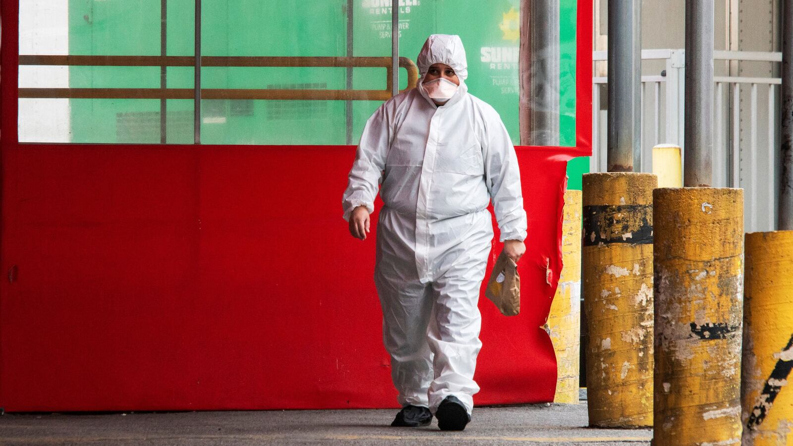A person wearing a PPE suit exits the Elmhurst Hospital center in New York City