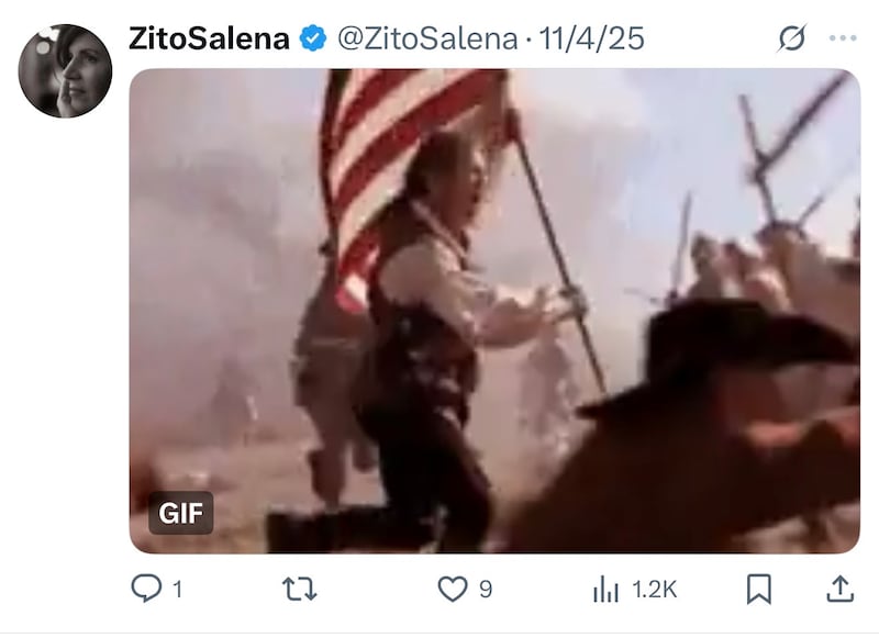 A man in revolutionary war outfit holding the U.S. flag.