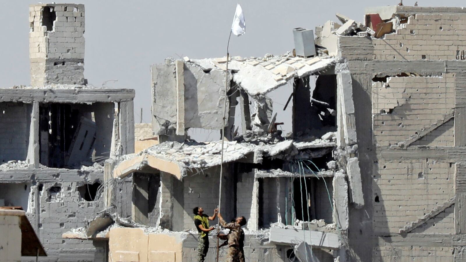 Fighters of Syrian Democratic Forces raise a white flag near the National Hospital complex where the Islamic State militants are holed up, at the frontline in Raqqa, Syria October 16, 2017.