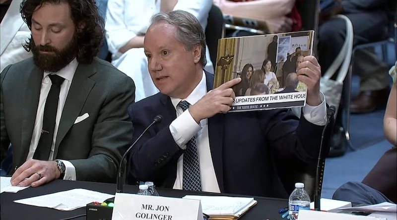 Public Citizen democracy advocate Jon Golinger, testifying at Capitol Hill, holds up a photo of Meredith O'Rourke attending a ballroom donor dinner at the White House last year.