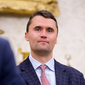 Turning Point USA co-founder Charlie Kirk stands in the back of the room as U.S. President Donald Trump speaks during a swearing in ceremony