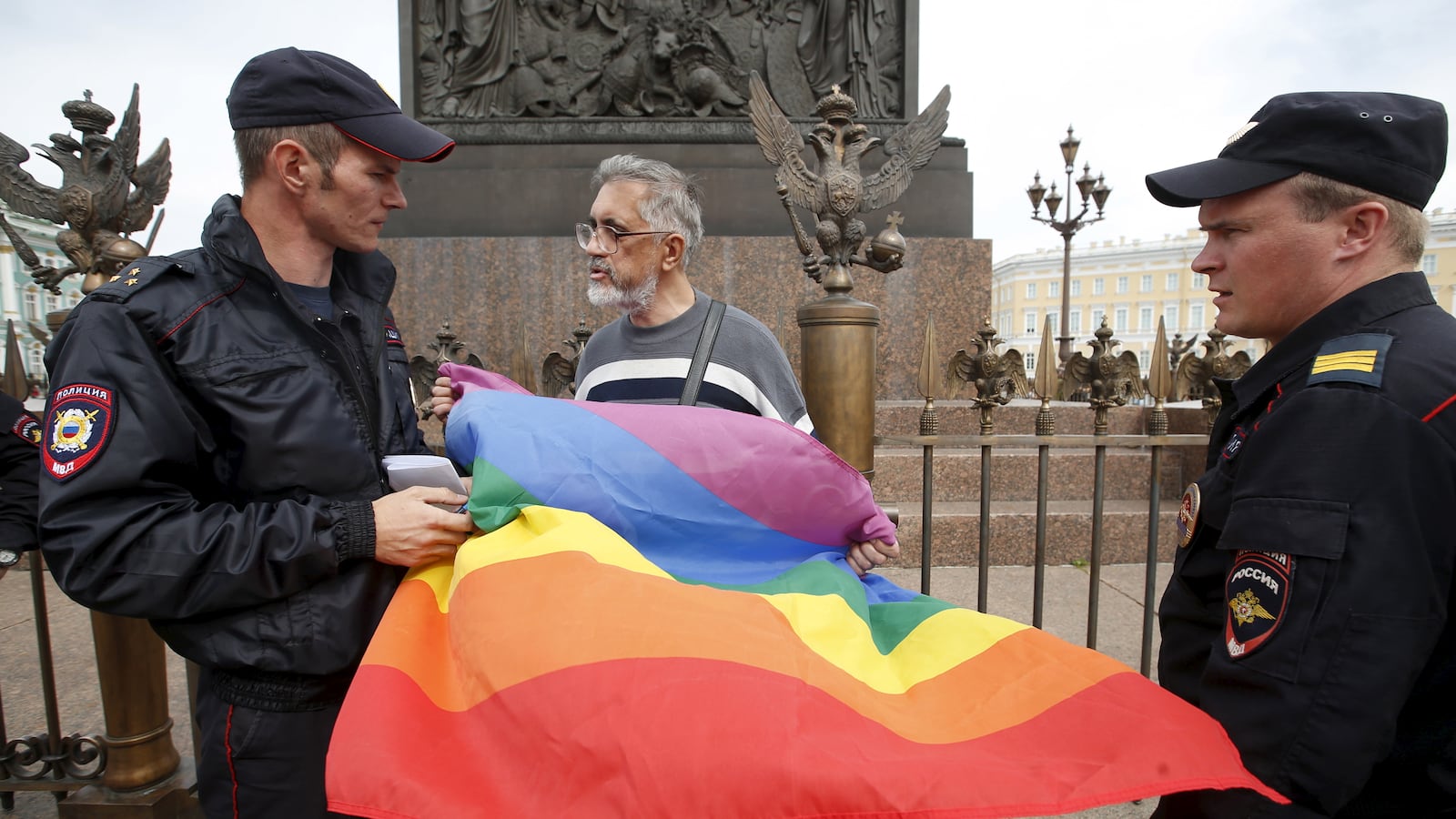 Policemen talk to a gay rights activist holding a rainbow flag during a protest in Dvortsovaya Square in St. Petersburg, Russia, Aug. 2, 2015.
