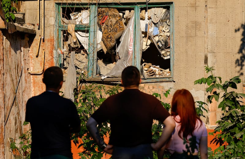 People stand in front of a heavily damaged multi-storey residential building following an overnight attack, what Russian-installed authorities called a Ukrainian drone strike, in the course of the Russia-Ukraine conflict in the town of Horlivka (Gorlovka) in the Donetsk region, a Russian-controlled area of Ukraine, June 24, 2026. REUTERS/Alexander Ermochenko