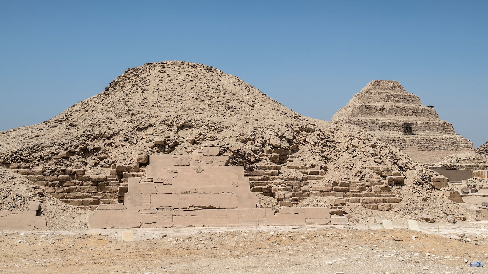 A picture taken on July 14, 2018 shows a view of pyramids in the Saqqara necropolis, about 35 kms south of the Egyptian capital Cairo, with the King Unas Pyramid (foreground) and the step pyramid of Zoser or Djoser (background). - Egypt's Ministry of Antiquities announced on July 14 the excavation of a mummification workshop discovered along with a communal burial place consisting of several burial chambers. The excavation is carried out by a Egyptian-German mission at the Saqqara necropolis complex south of the King Unas Pyramid. (Photo by Khaled DESOUKI / AFP) (Photo by KHALED DESOUKI/AFP via Getty Images)