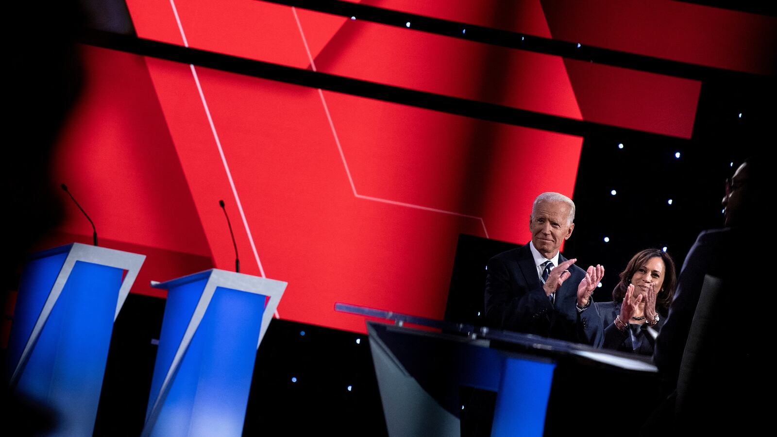 Kamala Harris and Joe Biden clap as other candidates take the stage ahead of the second round of the second Democratic primary debate during the 2020 presidential campaign season on July 31, 2019.