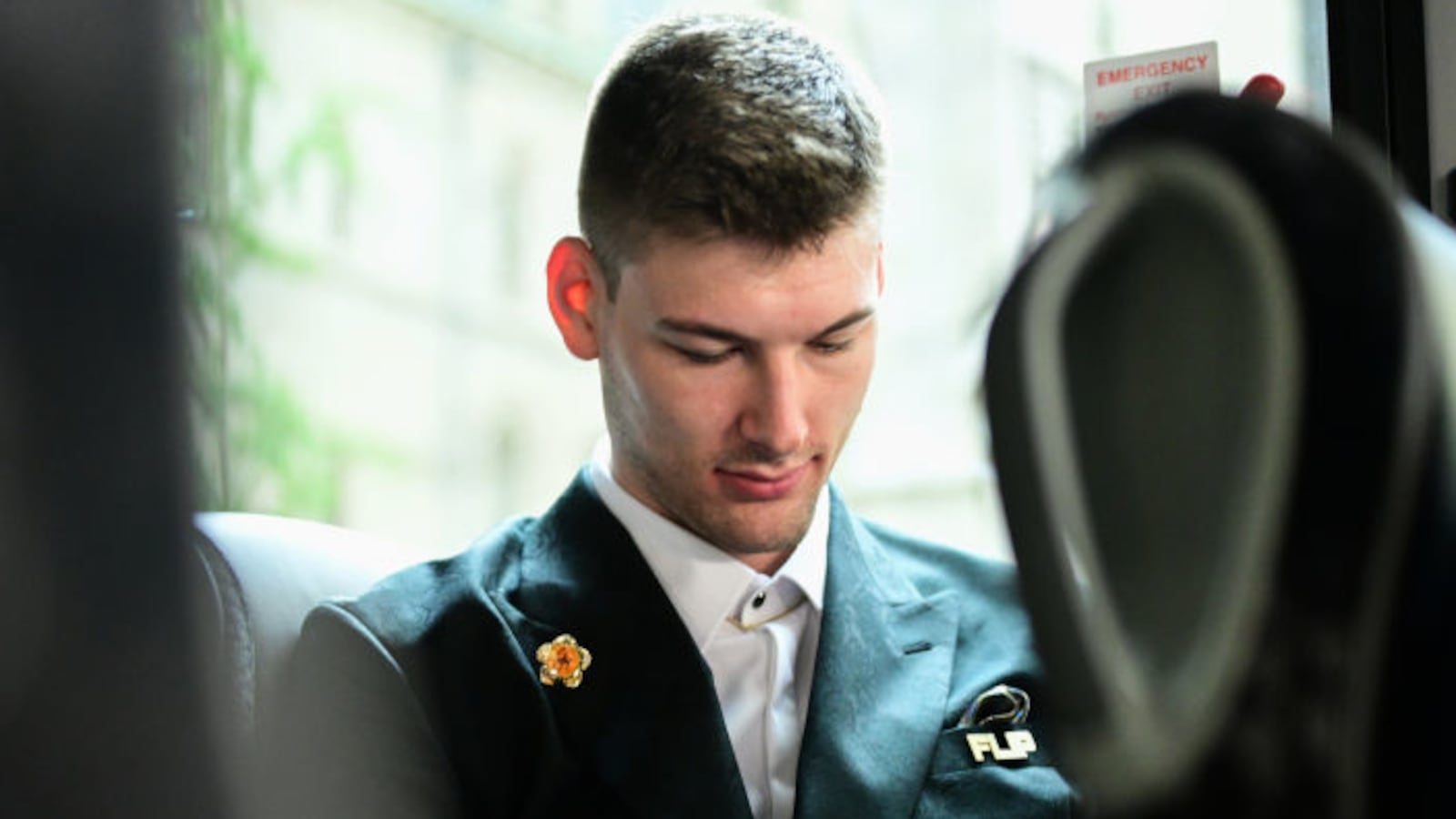 Kyle Filipowski, wearing a suit, scrolls on his phone.