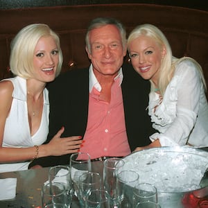 Models Holly Madison and Tiffany Holiday hug Playboy founder Hugh Hefner (center) during a birthday dinner party  for Hef's two other girlfriends, Bridget Marquardt and Izabella Kasprzyk, in Beverly Hills, California, on September 12, 2002 in Beverly Hills, California.