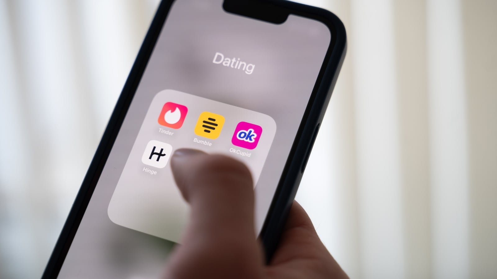 24 October 2024, Lower Saxony, Hanover: ILLUSTRATION - A woman holds a smartphone on which the dating apps Tinder, Bumble, OkCupid and Hinge are displayed.