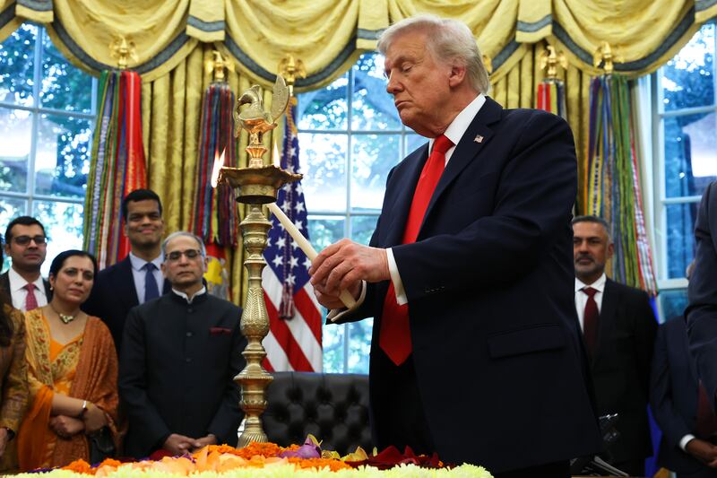 WASHINGTON, DC - OCTOBER 21: U.S. President Donald Trump lights a diya candle during an event celebrating Diwali in the Oval Office of the White House on October 21, 2025 in Washington, DC. Trump held the event to honor the Hindu festival that symbolizes the victory of light over darkness. (Photo by Anna Moneymaker/Getty Images)