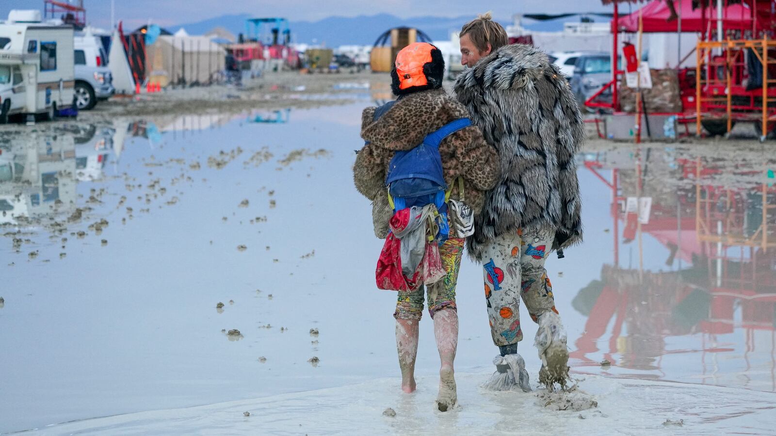 Dub Kitty and Ben Joos, of Idaho and Nevada, walk through the mud at Burning Man after a night of dancing with friends in Black Rock City