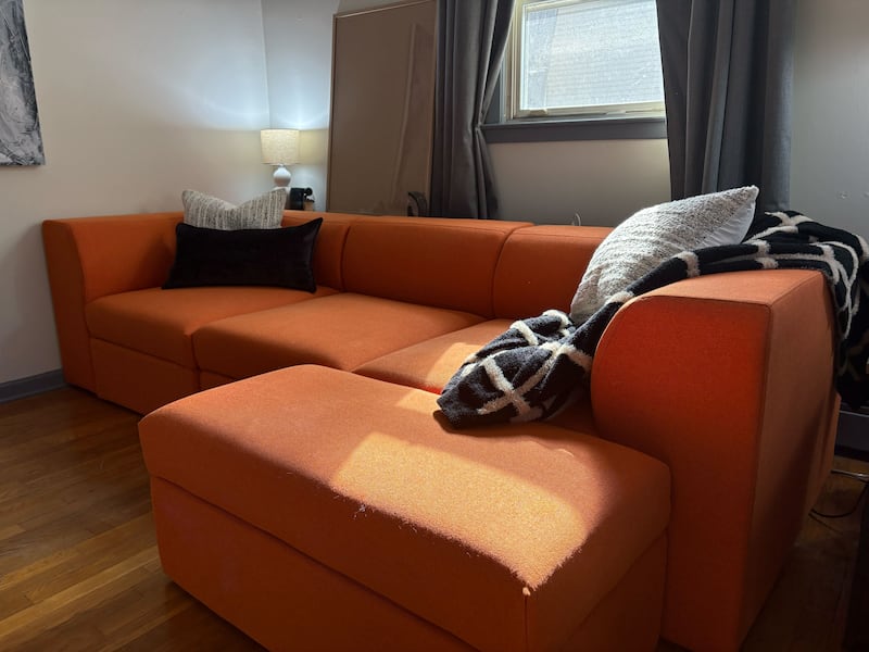 The Atmosphere couch in tangerine, with black and white pillows and blankets draped around it.